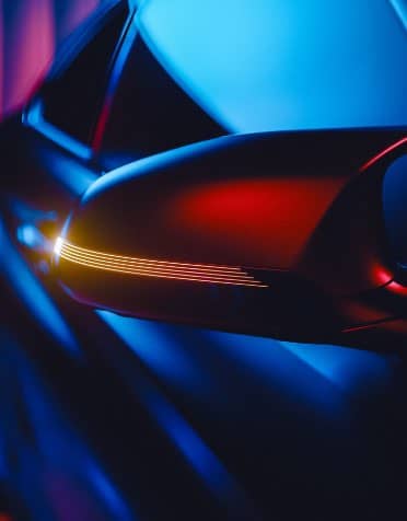 Close-up of a car’s side mirror with illuminated turn signal lights, featuring dramatic blue and red lighting for a sleek, modern look—perfect inspiration for spare parts upgrades.