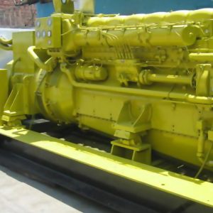 A 1 unit 1000 kVA Pielstick used and repaired generator, industrial yellow, with multiple cables and control panels, installed outdoors on concrete for an international client.
