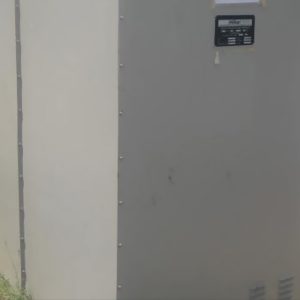 A close-up of a One Set Of Secondhand Natural Grounding Resistor shows a large, light gray metal enclosure with a small black label on the upper section, standing outdoors on grass.