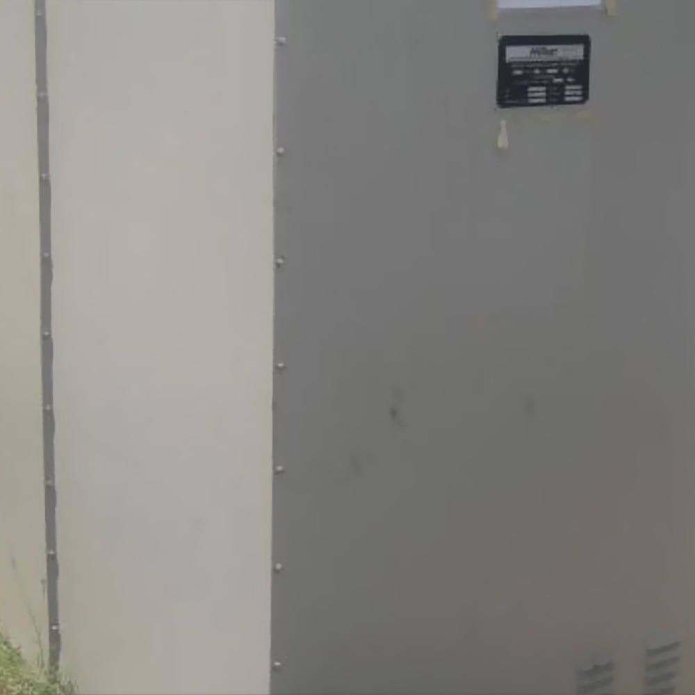 A close-up of a One Set Of Secondhand Natural Grounding Resistor shows a large, light gray metal enclosure with a small black label on the upper section, standing outdoors on grass.