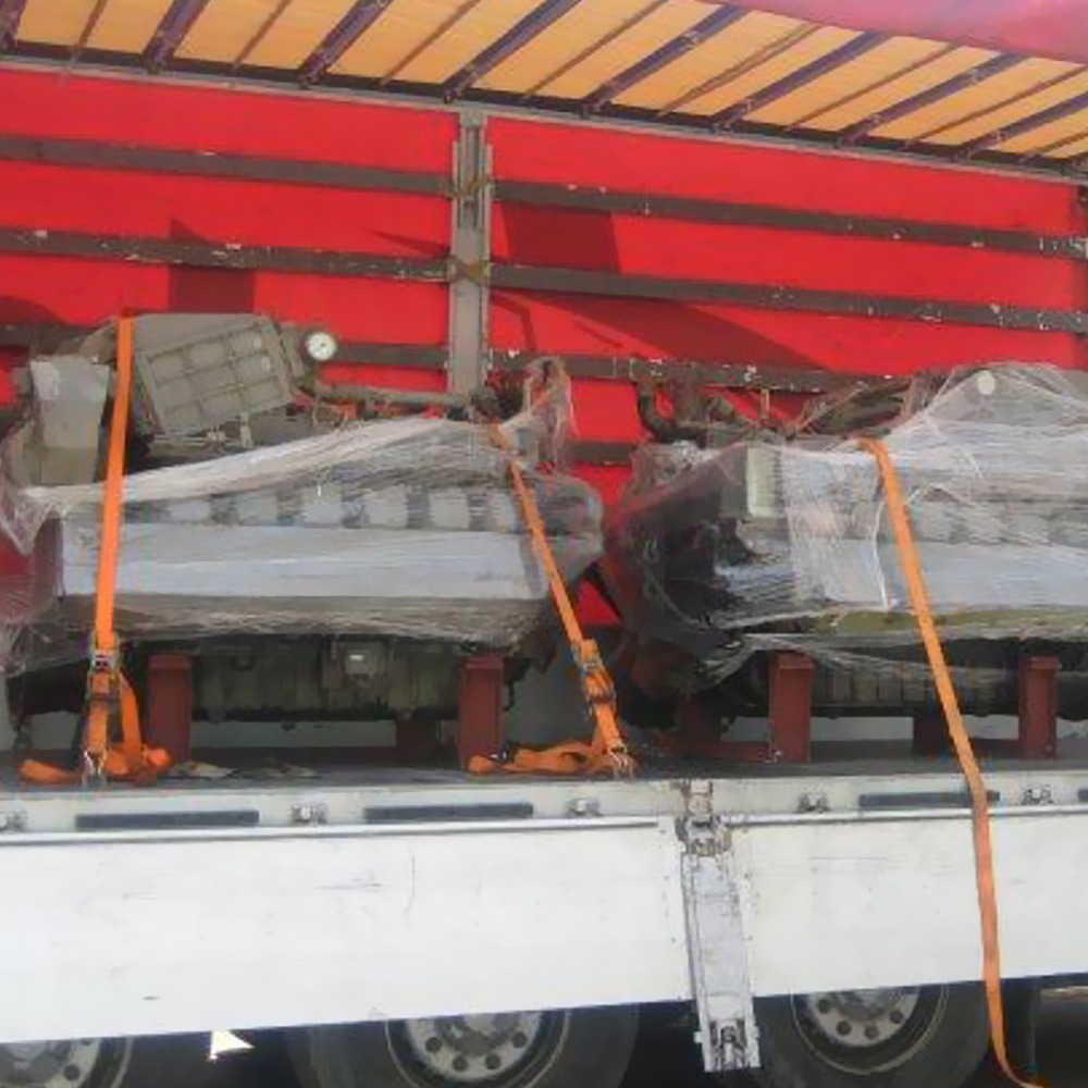 Two sets of DEUTZ (12M816) used diesel engines only, wrapped in plastic and secured with orange straps, are loaded on a flatbed truck with a red cover.