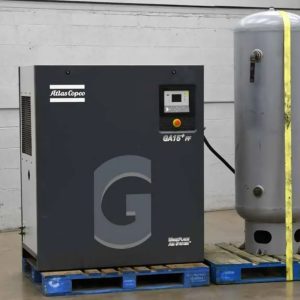 New ATLAS COPCO AIR Compressor (GA15) auxiliary for a Taurus 60 GTG Plant, with vertical air tank on pallets, placed indoors against a white wall with concrete flooring—ideal for plant applications.