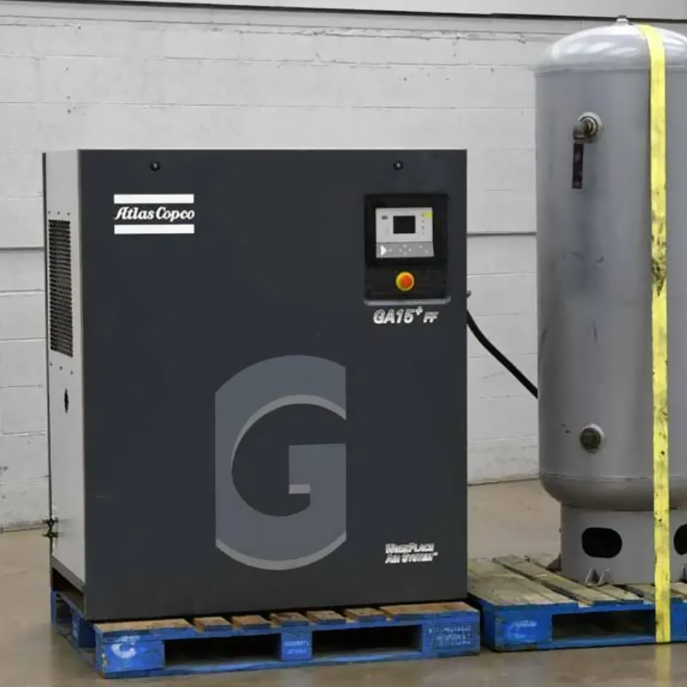 New ATLAS COPCO AIR Compressor (GA15) auxiliary for a Taurus 60 GTG Plant, with vertical air tank on pallets, placed indoors against a white wall with concrete flooring—ideal for plant applications.