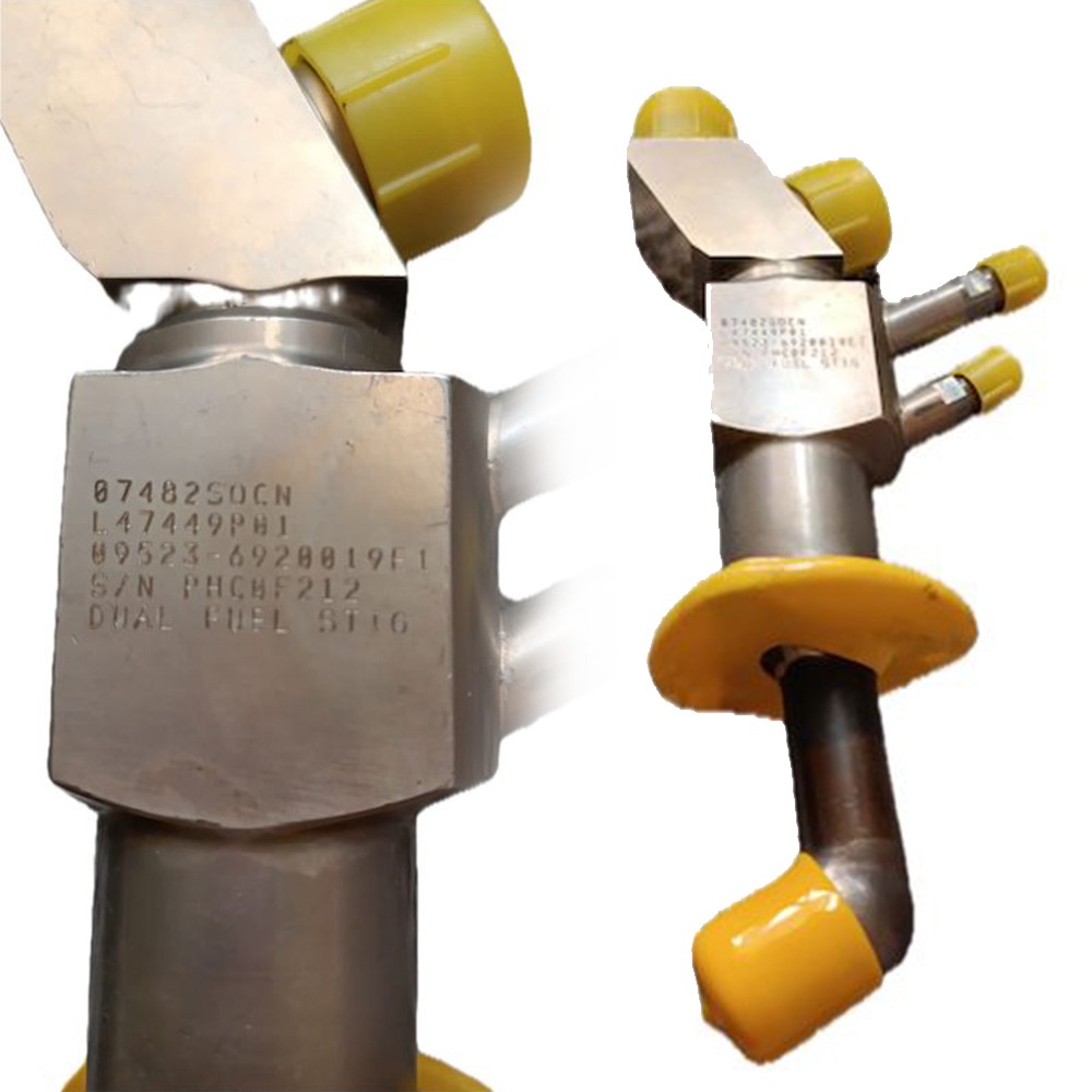 A metallic component with serial numbers engraved on it, featuring yellow plastic caps on its ends and connectors. The item appears industrial—possibly a valve or fuel injector—and is identified as a gasturbine spare part for the LM2500 series. Specifically, it is one of four overhauled OH Dual Fuel DF Nozzles L47449P01, shown from two angles on a white background.