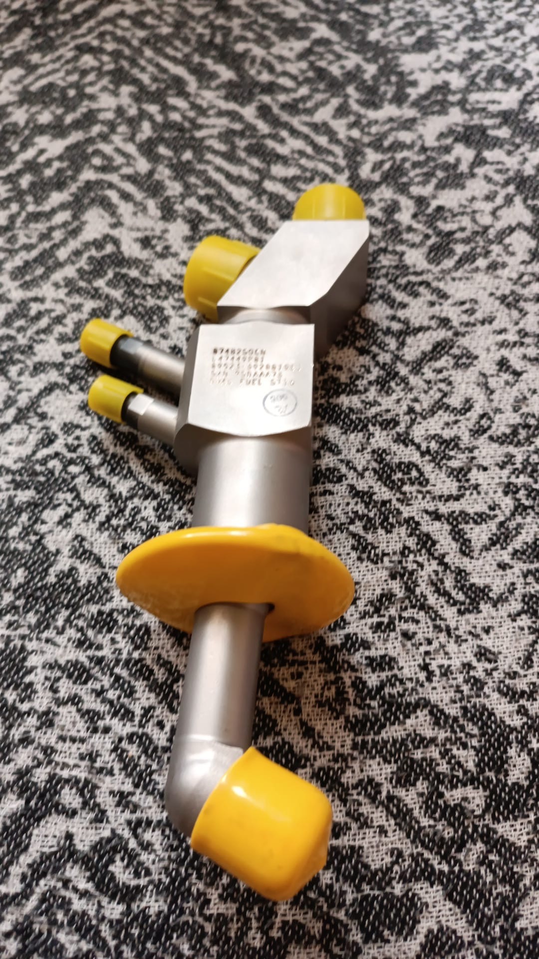 Four overhauled OH Dual Fuel DF Nozzles (L47449P01), each with multiple cylindrical extensions and yellow caps, resembling gasturbine spare parts, rest on a black and white patterned surface.
