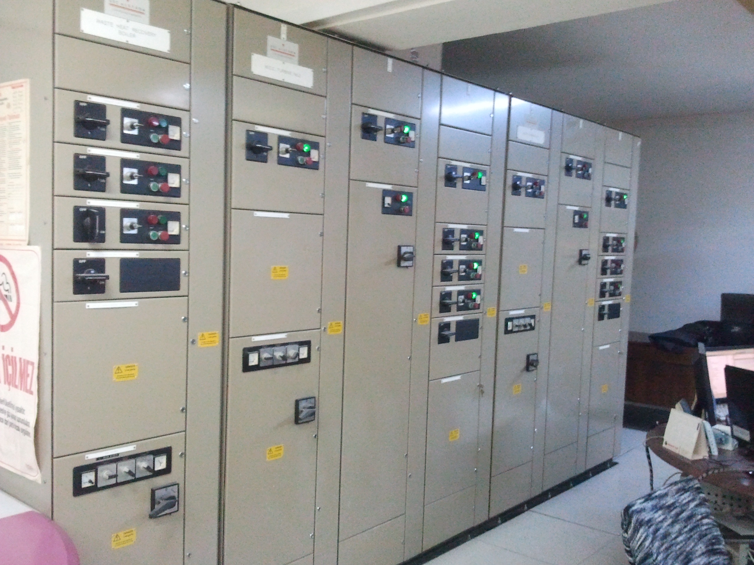 A row of beige electrical control panels with various switches, buttons, and indicator lights, installed along a wall in an indoor industrial or utility room—commonly used to support Siemens SGT 200 Gas Turbine Packages operations and manage critical spare part systems.