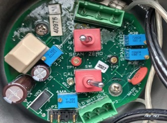 A close-up of a green circuit board for the Gas Analyser Transmitter WILSON DET-TRONICS 5 Each, featuring red and blue adjustment knobs, new green and beige terminals, labeled parts, wires, and connectors as a spare part.