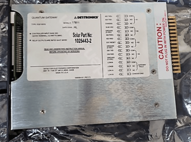 A rectangular Det-tronics QUANTUM GATEWAY LOCAL CONTROL UNIT EQ2100CG LOGIC CONTROLLER, new or used, has labeled ports and warning stickers like CAUTION: DO NOT PLUG WITHOUT PERMISSION, on a metallic surface, compatible with LM6000 systems.
