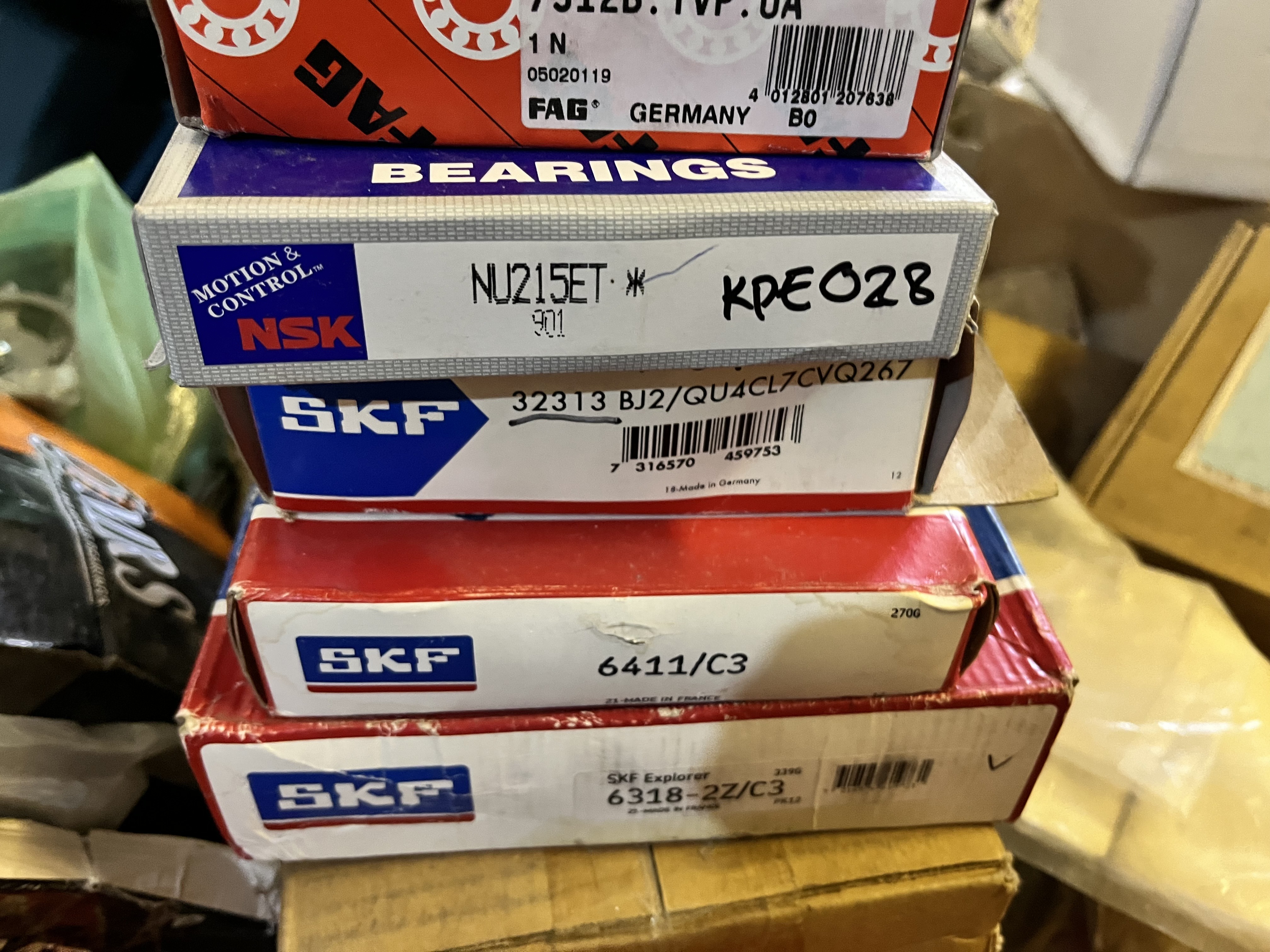 A close-up of four stacked bearing boxes from brands NSK and SKF, including part numbers like NJ215ET and 6411/C3, surrounded by packaging—ideal for LM6000 gas turbine maintenance or use in refurbished mechanical assemblies.