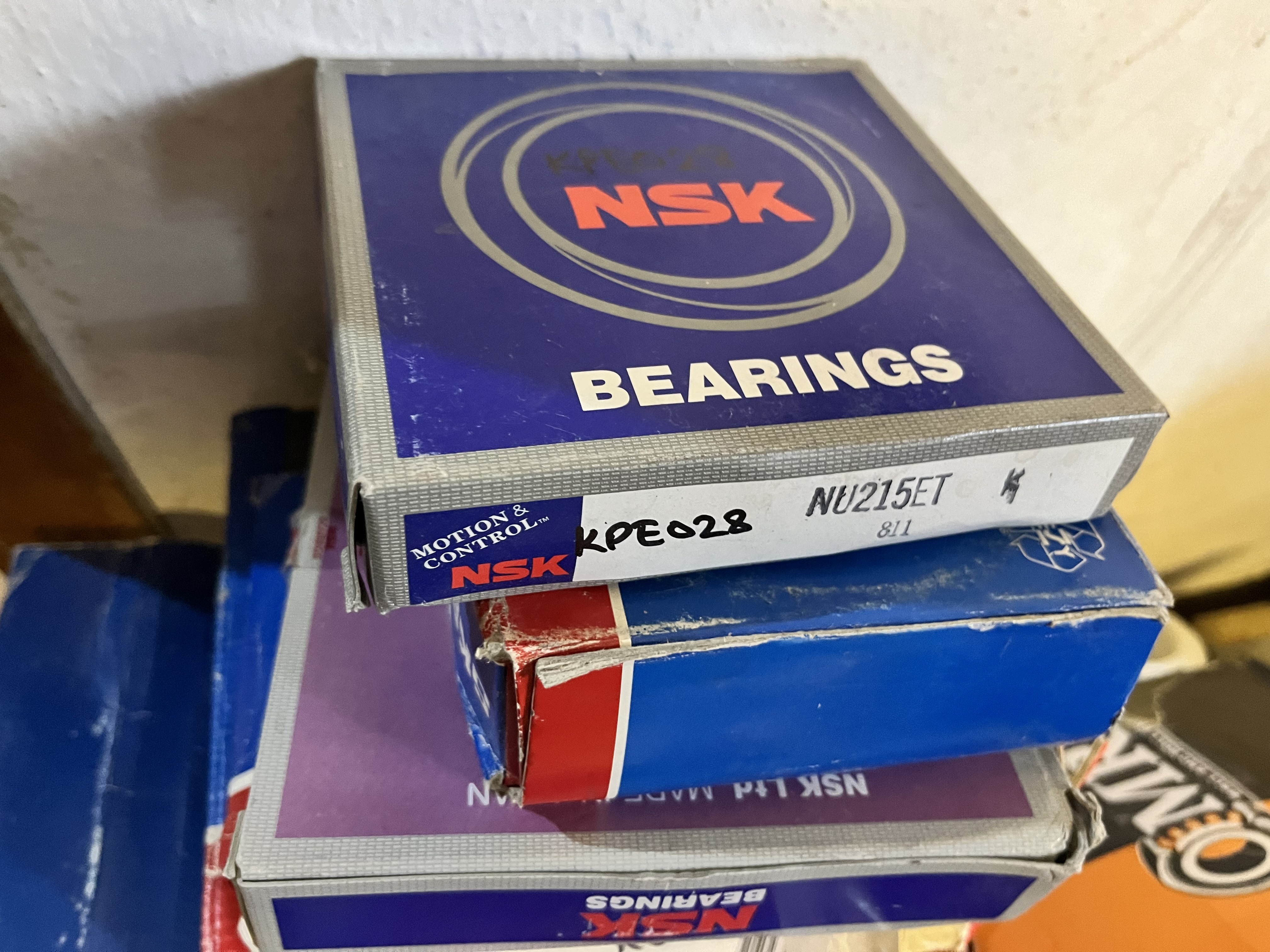 A close-up of three stacked boxes of used NSK bearings, with the top box labeled NSK BEARINGS NU215ET. The slightly worn blue boxes may be suitable for applications such as the LM6000 gas turbine.