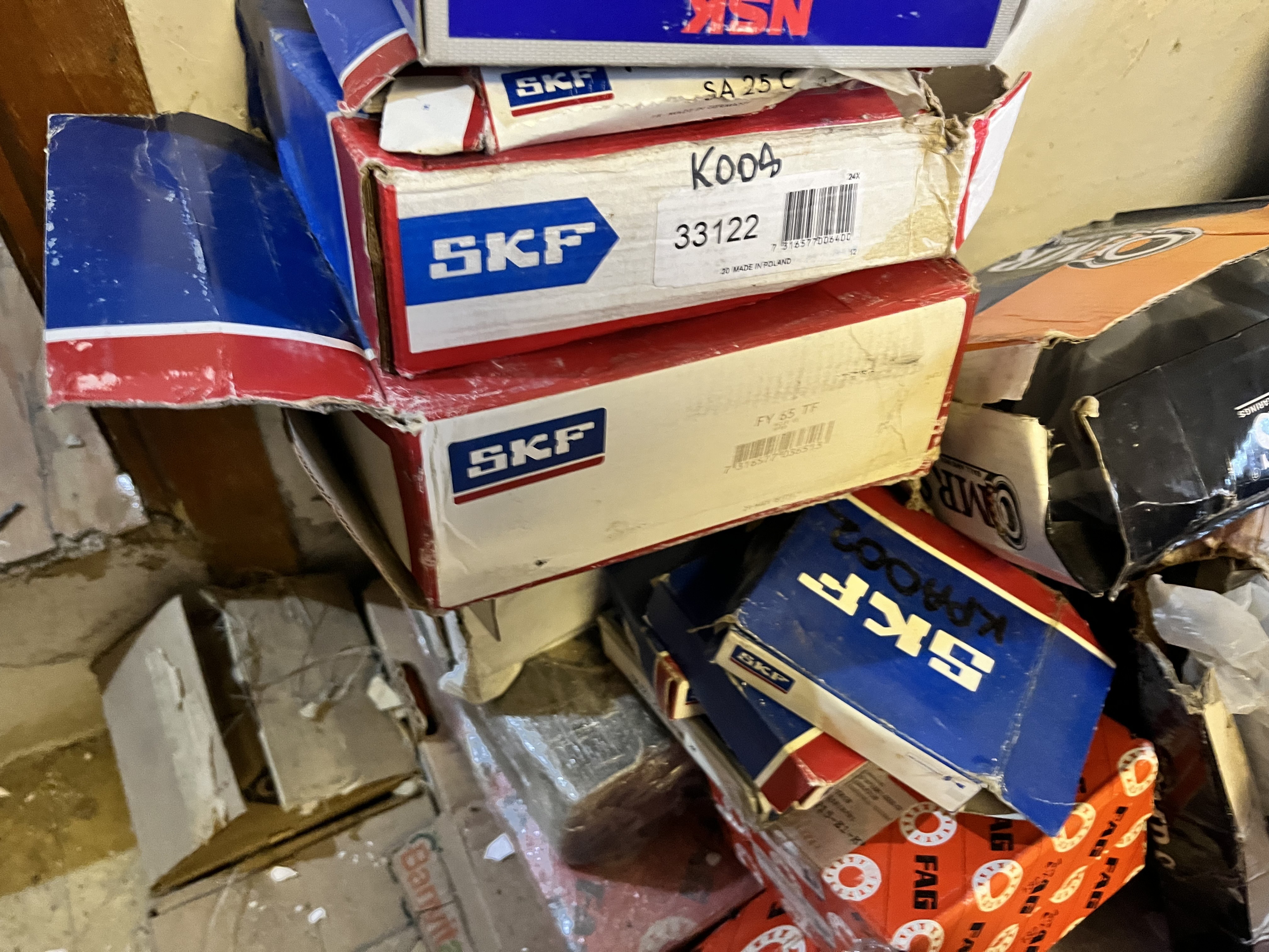 Several stacked cardboard boxes, mostly labeled SKF in blue and white, are seen in a cluttered storage space, possibly containing refurbished parts for an LM6000 gas turbine among other items.