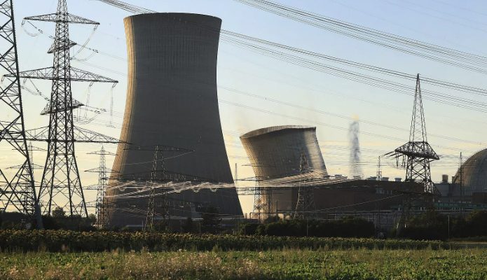 Cooling towers and power lines at a nuclear plant, with green vegetation in the foreground and clear sky; an LM2500 Gas Turbine spare parts inventory 001 may support local energy operations.