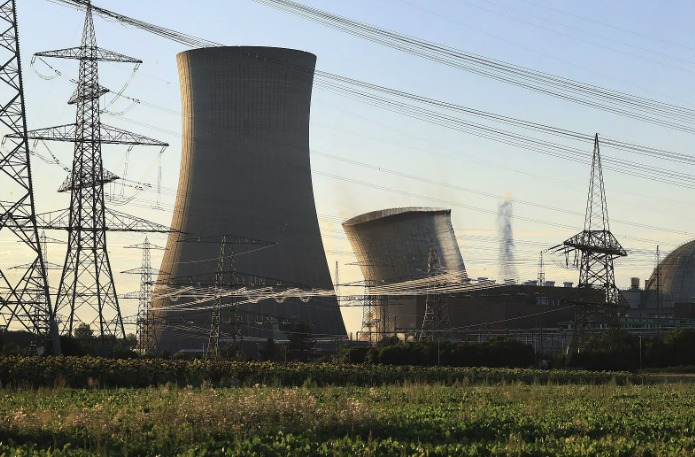 Cooling towers and power lines at a nuclear plant, with green vegetation in the foreground and clear sky; an LM2500 Gas Turbine spare parts inventory 001 may support local energy operations.
