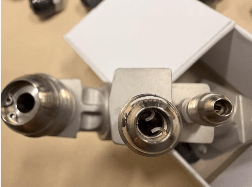 Close-up of a full set of fuel nozzles L31809P12 FOR LM2500, showing two different nozzle sizes resembling turbine attachments, against a blurred background with a white rectangular object.