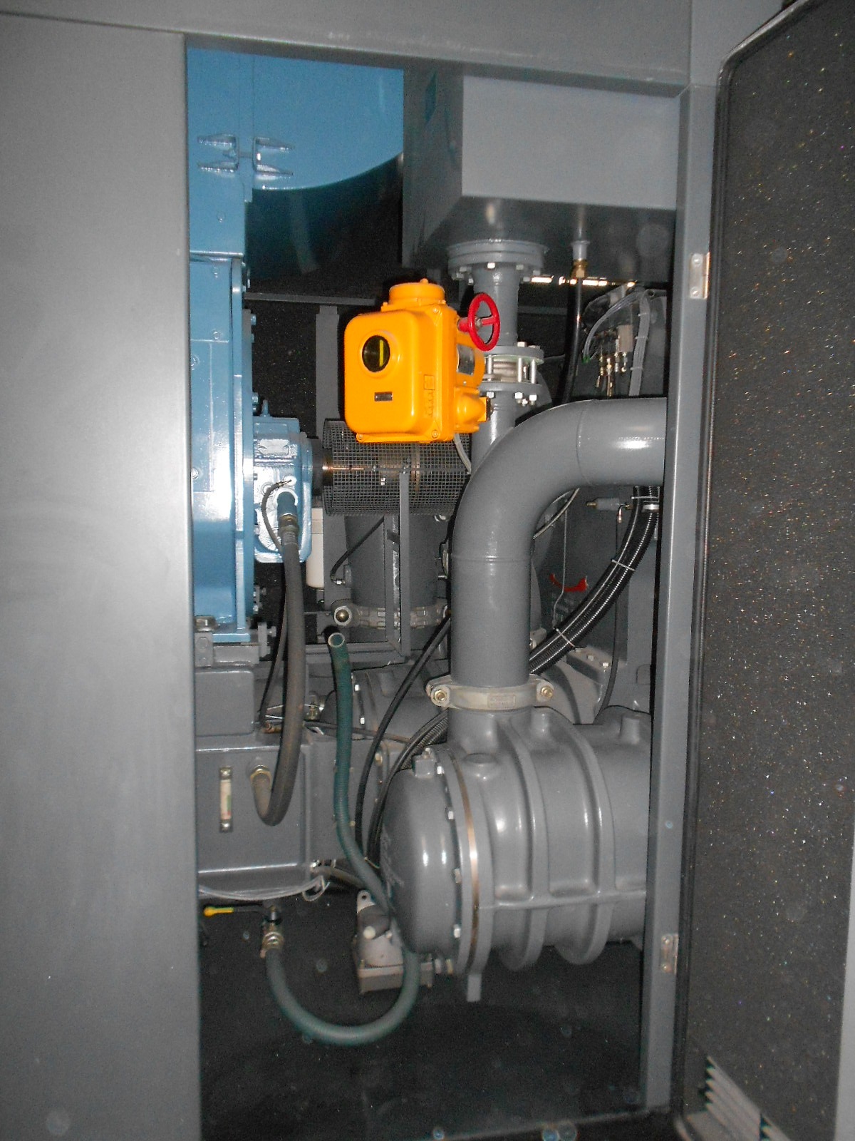 Interior of an ATLAS COPCO ZH 10000-6-7PL AIR COMPRESSOR revealing gray components, pipes, hoses, and a yellow valve inside the opened metal enclosure.