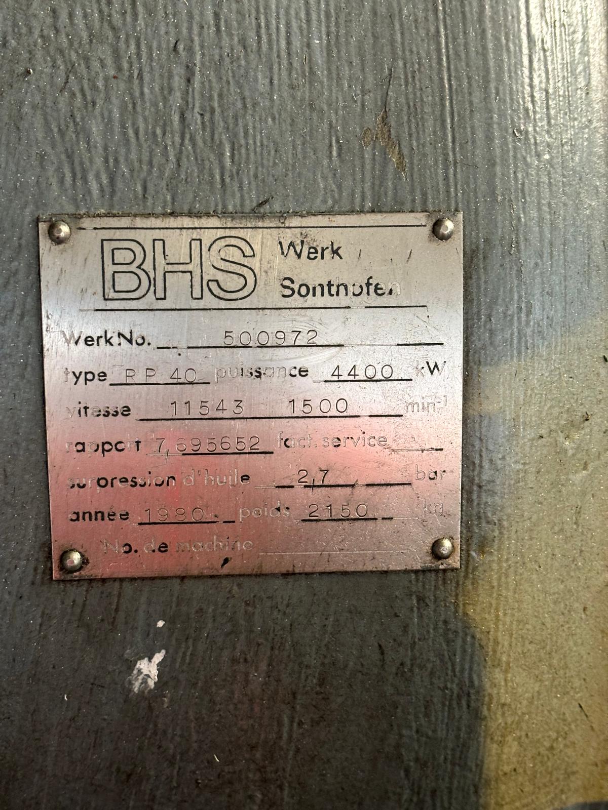 A metal identification plate on a machine, featuring the BHS logo and information in French about power, speed, pressure, year, and weight, including fields like puissance, vitesse, pression dhuile, and more.