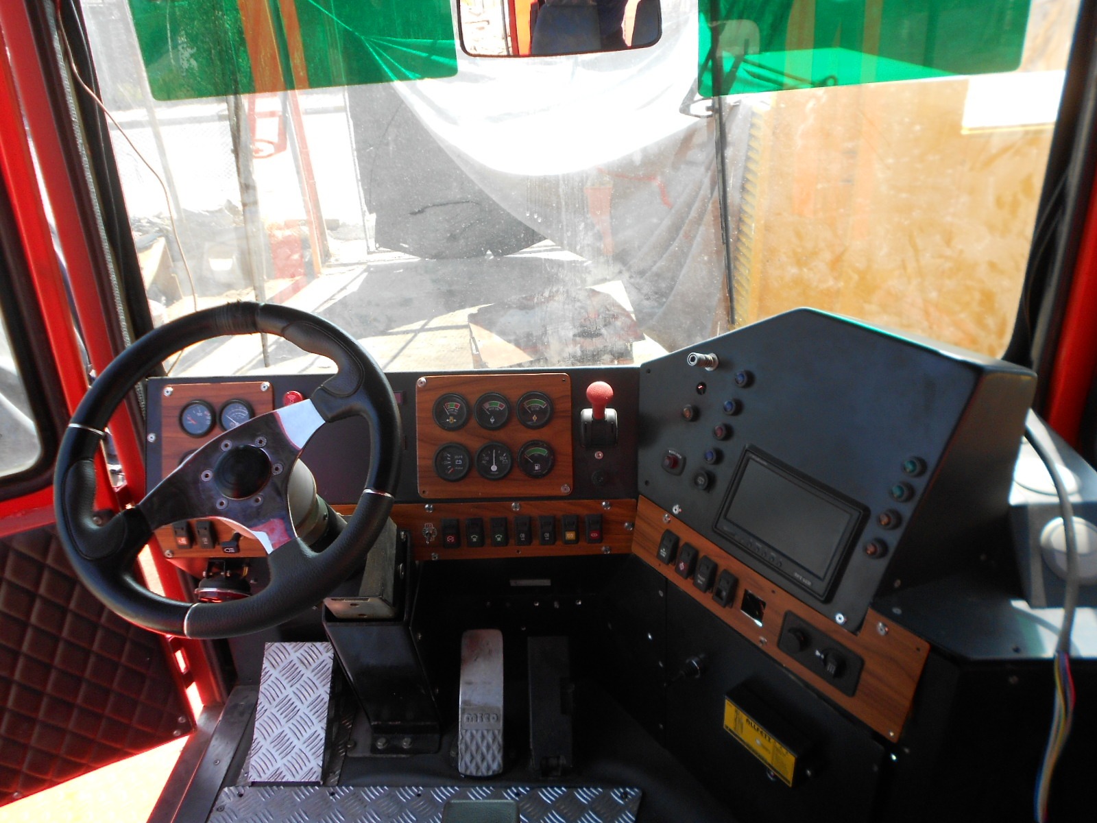 Interior view of the AVAILABLE PALING HEAVY TRANSPORTER cab, featuring a steering wheel, pedals, dashboard with gauges, buttons, levers, digital display, and surrounded by windows.
