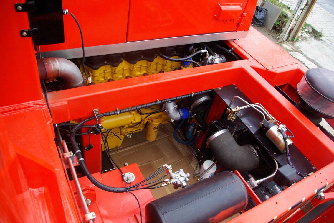 Close-up view of a bright red vehicle’s engine compartment, featuring yellow engine components, black hoses, and various cables—all arranged with the precision of an AVAILABLE PALING HEAVY TRANSPORTER in the engine bay.