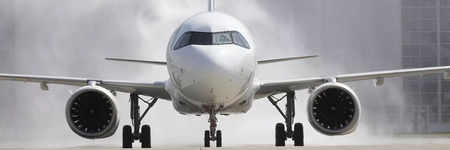 A front view of a commercial airplane on the runway with water spraying in the background, possibly during a celebratory water salute for new SURPLUS STOCK AVAILABLE FOR SALE: Airbus A320, A319, ATR72 Component Tyre EATON products, Boeing 737 fleet.